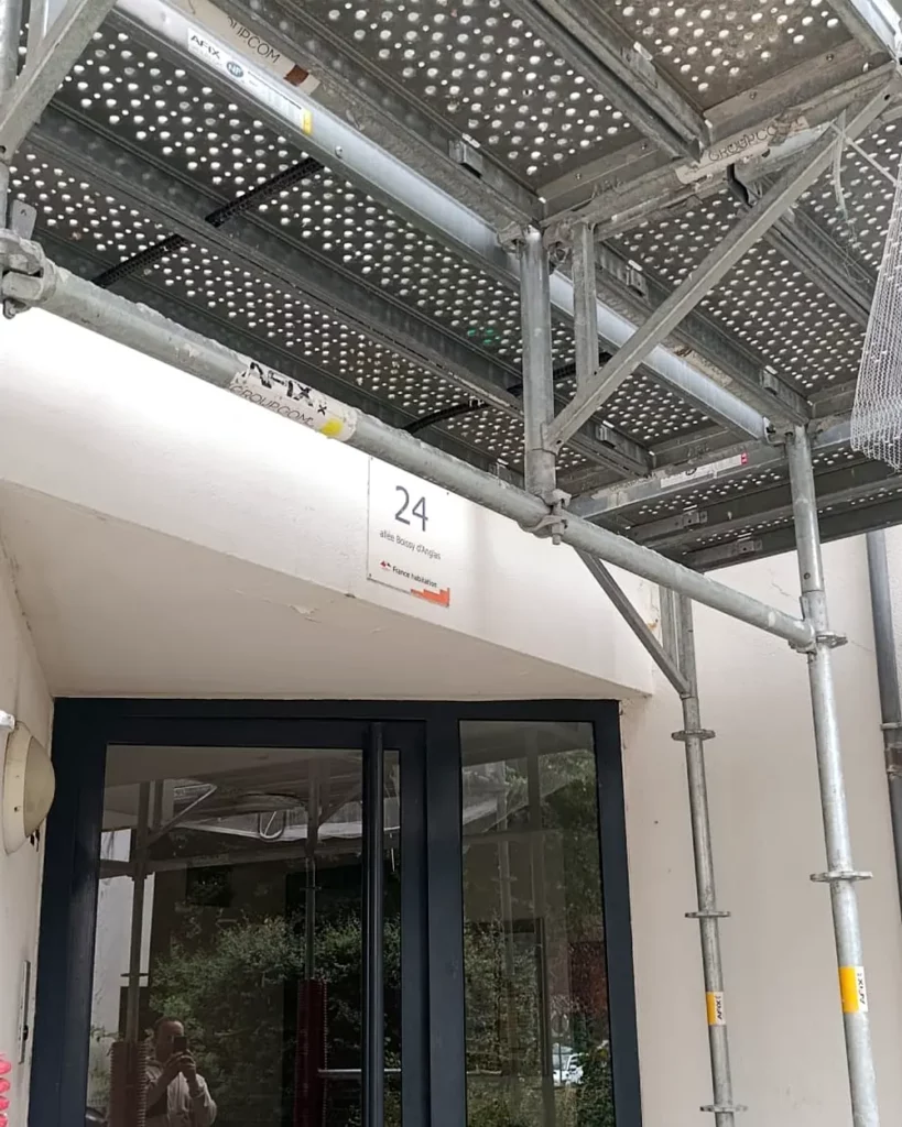 Accès au hall d'entrée maintenu et protégé sous un plancher d'échafaudage, bâtiment habité