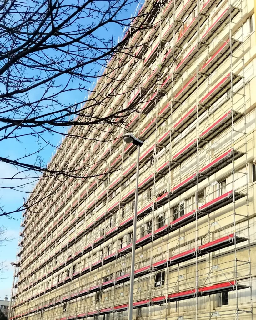 Échafaudage Matrix Service montant jusqu'au pignon d'un immeuble de grande hauteur, plateaux de travail et garde-corps à chaque niveau